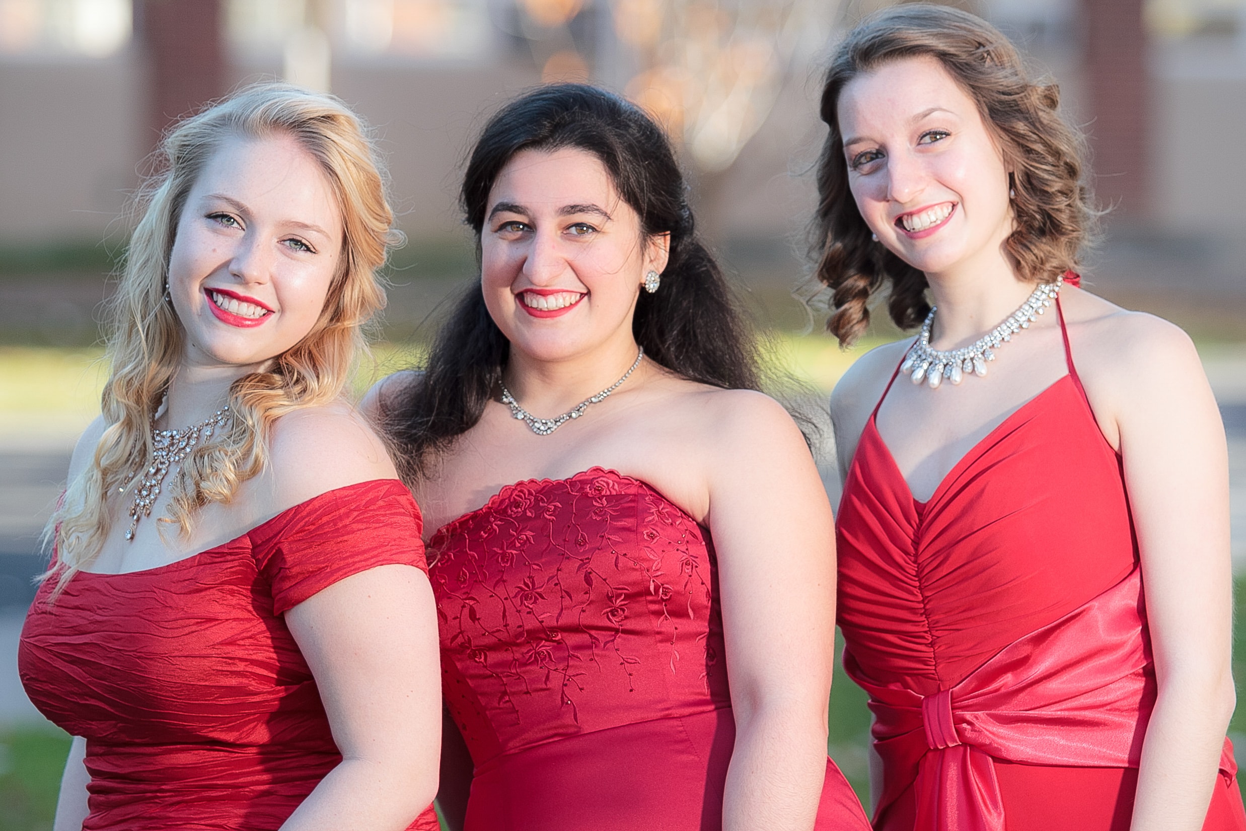 Three women in red formal dresses smiling
