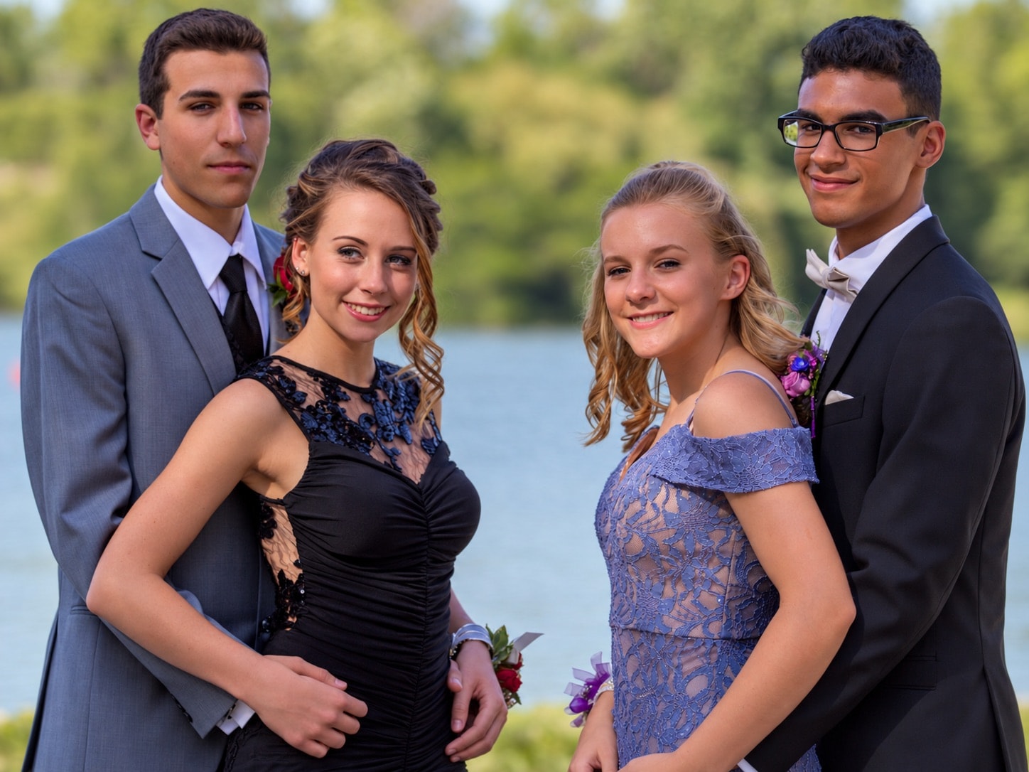 Four young people in formal prom attire by the water