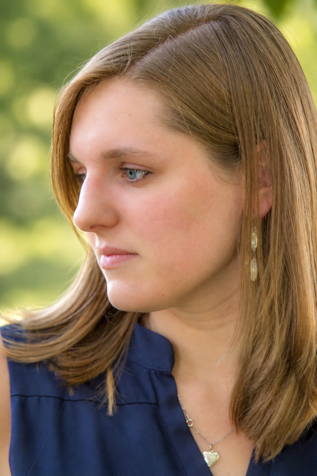 Woman in profile with straight auburn hair and blue top, outdoor portrait