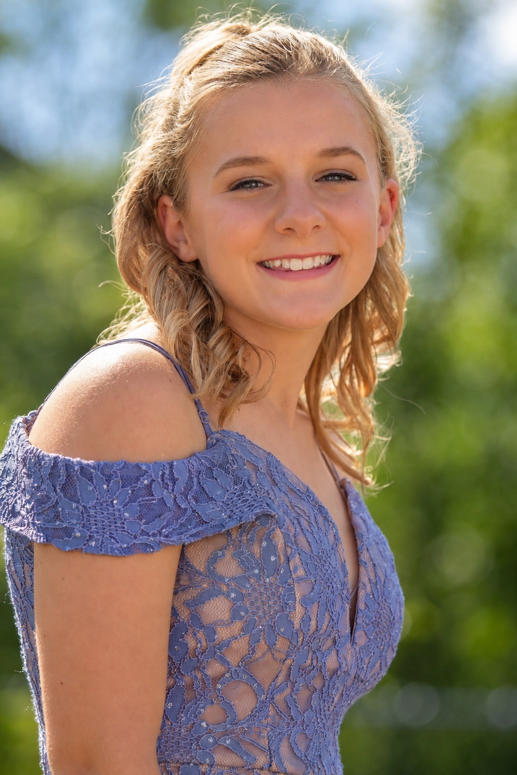 Young woman smiling in blue lace dress, outdoor portrait